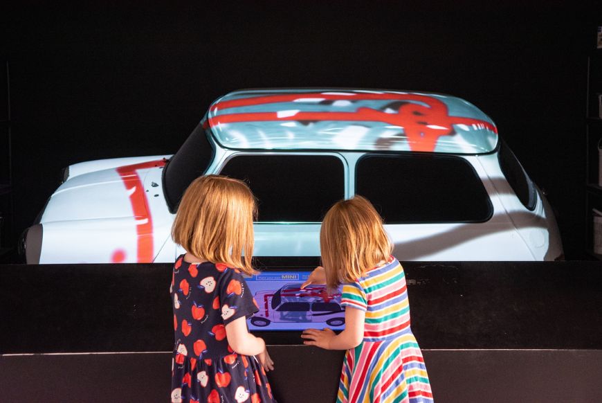two children looking at a car